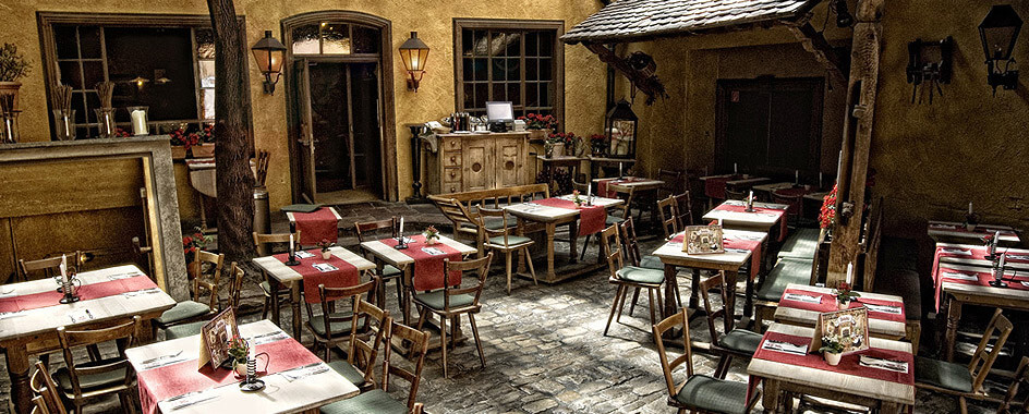 Innenhof des Backöfele mit Holztischen und rot karierten Tischdecken