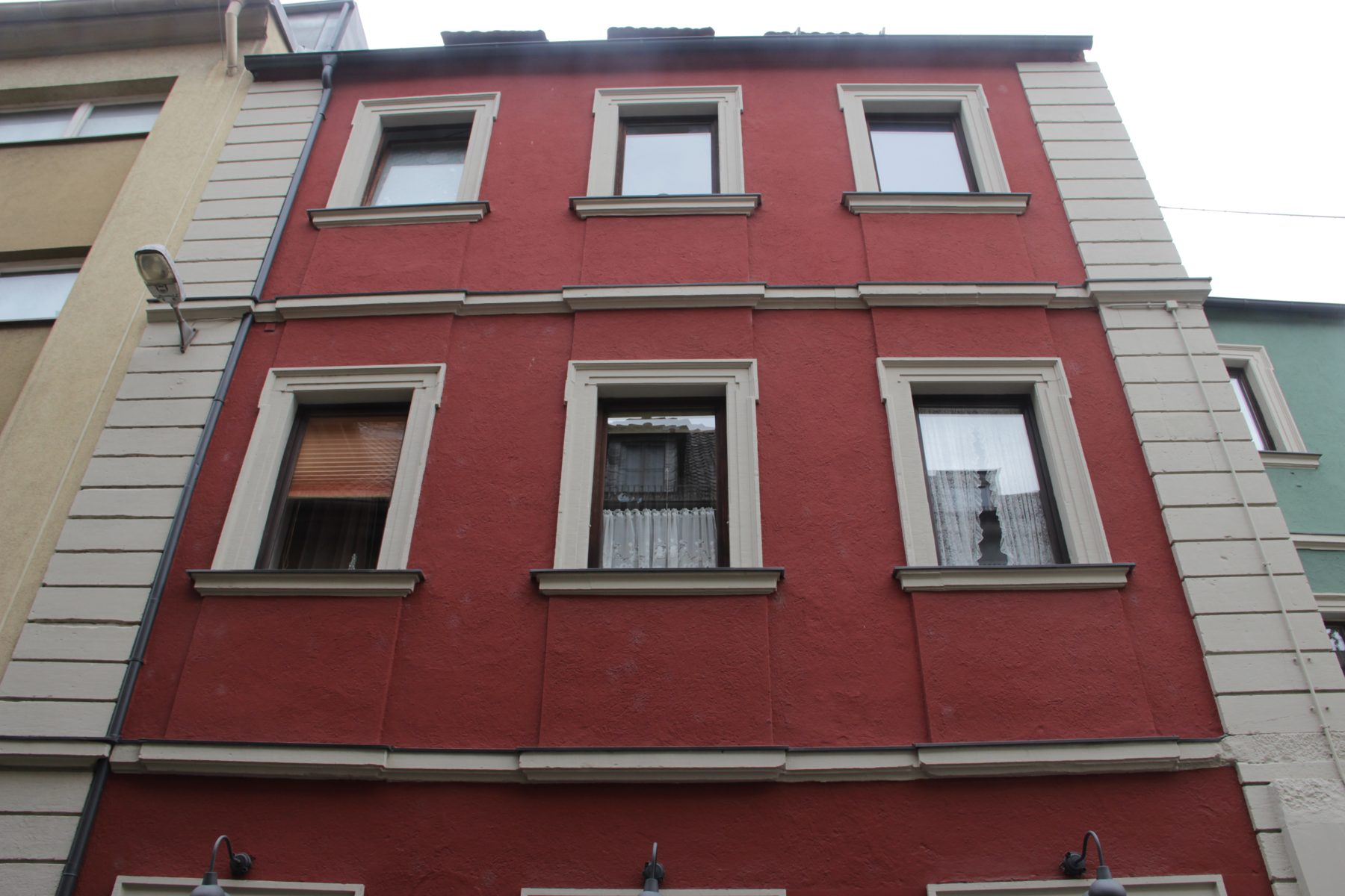 Obergeschosse des Hauses Bockgasse 3 in Würzburg: rote Putzfassade mit hellen, geohrten Fensterrahmungen