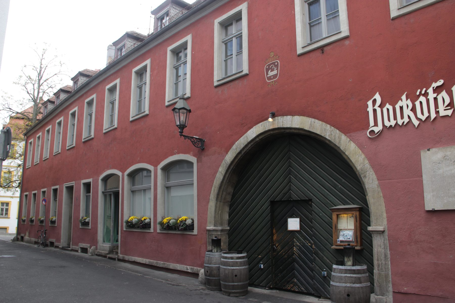 Backöfele-Haus in der Ursulinergasse 2 in Würzburg: langgestreckte rote Fassade mit großer Toreinfahrt und Schriftzug Backöfele